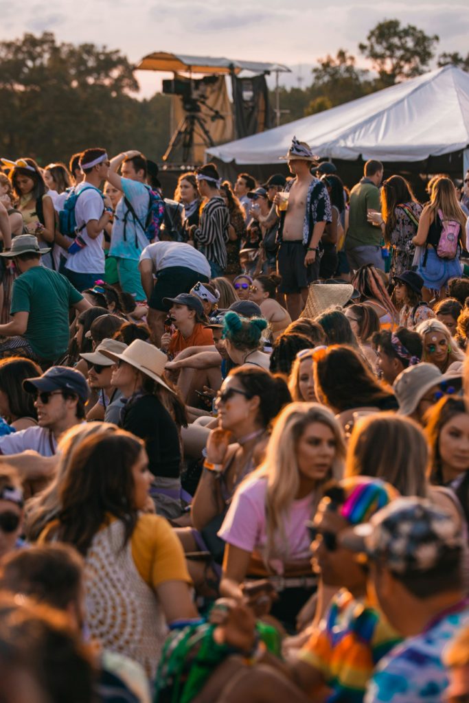 A lively crowd enjoying an outdoor music festival under tents and open skies.